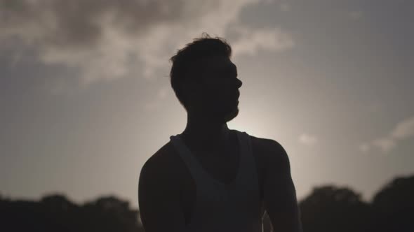 Man In Park Stretching Before Excercise Whilst Weing Silouetted By The Sun In Slow Motion - Ungraded