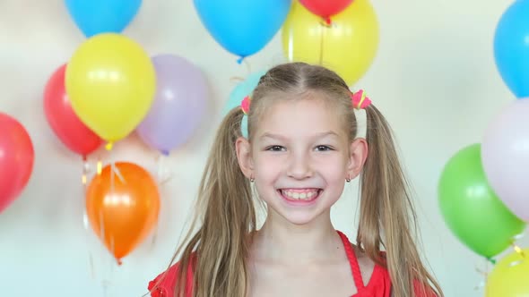 Blonde Girl in Dress Smiles Standing Against Air Balloons