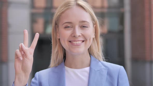 Sign of Victory By Young Businesswoman Standing Outdoor