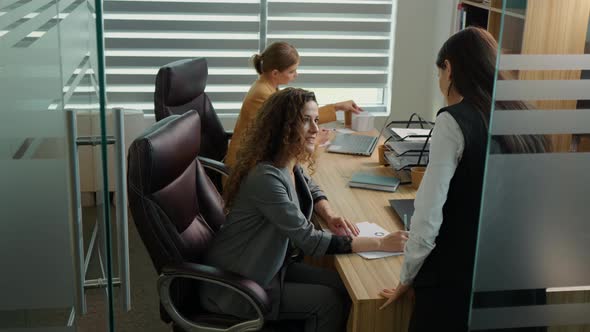 Businesswoman giving assignments to employee in modern office.