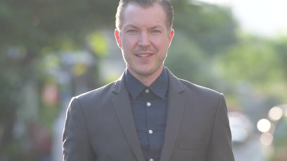 Face of Happy Young Handsome Businessman in Suit Smiling Outdoors