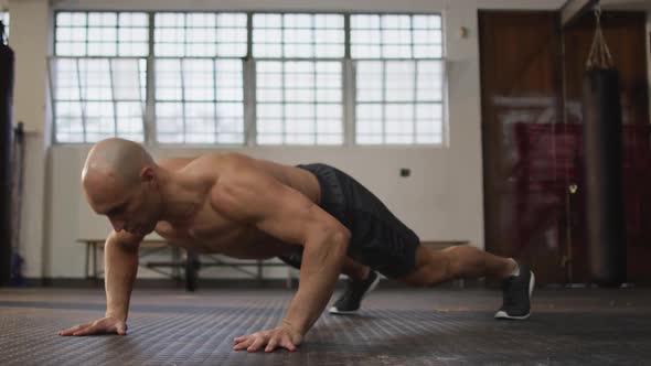 Caucasian muscular shirtless bald man exercising, doing push ups