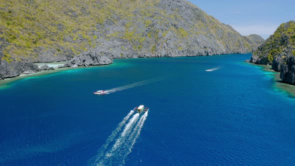 Drone Follow Island Hopping Boats in Strait Between Matinloc and Tapiutan Island in El Nido Palawan