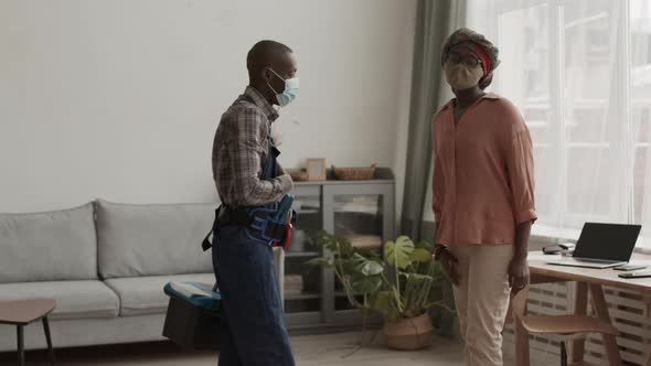 African-American Housewife Wearing Mask Telling Handyman What to Fix