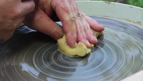 a Caucasian Male Potter Cleans Clay From a Rotating Potter's Circle