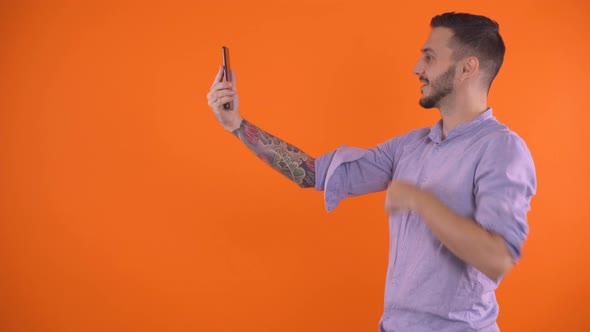 Man with Tattoo Sleeve on Arm Using Smartphone To Video Call a Friend, Studio Shot