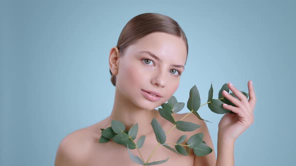 Portrait of Attractive Millennial Woman Holding Plant Branch While Looking to Camera 