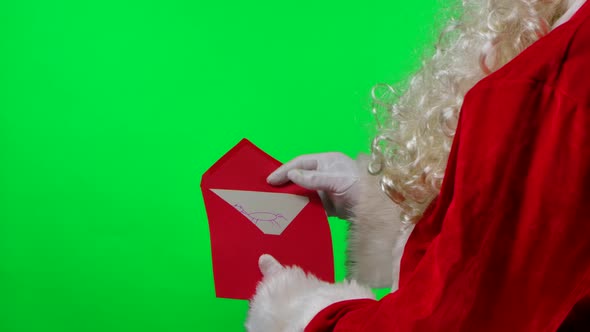 Santa Claus with a Beard in White Gloves and a Red Suit is Holding an Envelope with a Letter From a