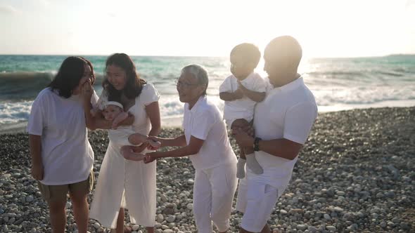 Positive Asian Multigenerational Family Standing in Sunlight on Turquoise Mediterranean Sea Beach