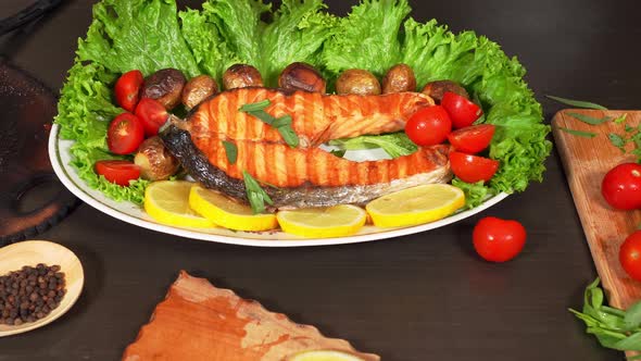 Womans Hand Adds  Tarragon Herbs On The Fried Salmon On The Plate With Lettuce , 