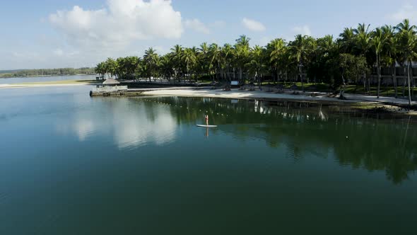 Aerial view of a blonde girl paddling a surfboard, Mauritius.