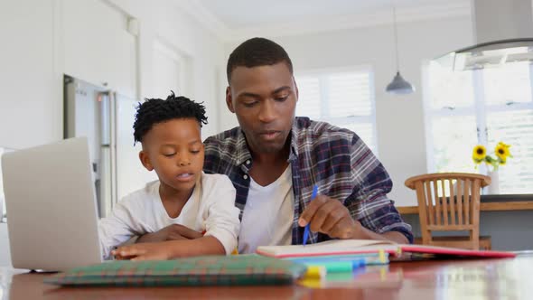 Front view of black father helping his son with homework at comfortable home 4k