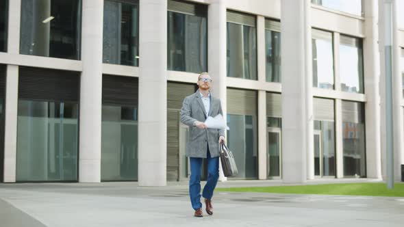 Businessman Walking Out Office Building and Throwing Paper Celebrating Transition To Remote Work