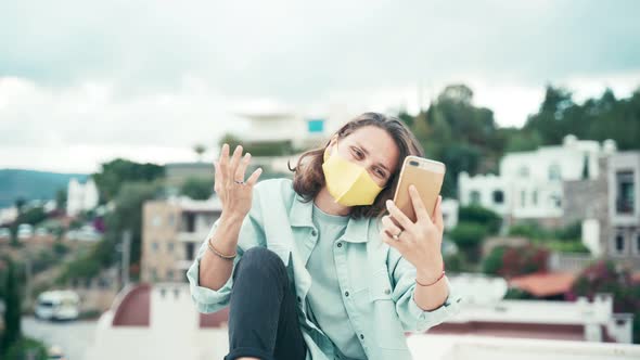 Young Woman in Yellow Mask Recording Video for Social Media with Her Smartphone