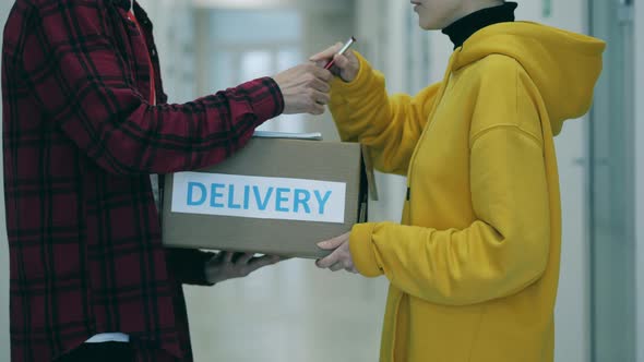 Courier Gives a Box To a Client Who Signs Delivery Documents