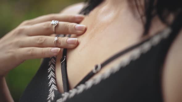 Close up of young female sweating on a hot day. Woman gently touching her chest with fingers moving