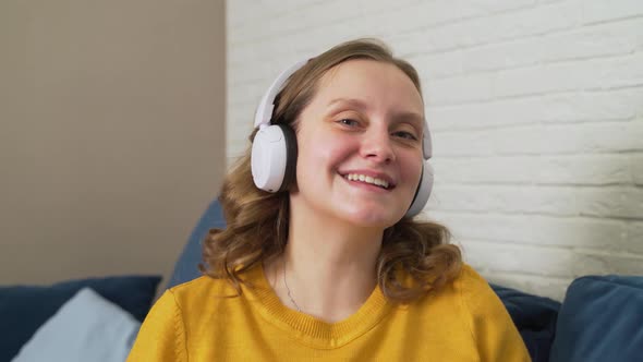 Woman with Blue Eyes in White Headphones Listens to Music and Dances