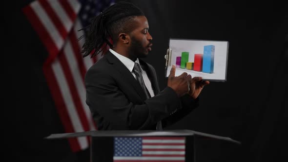 Handsome African American Man Pointing at Graph Talking with USA Flag at Black Background