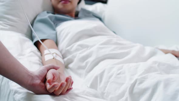 Female Patient Lying on Medical Couch while Hospital Worker Stroking Her Hand