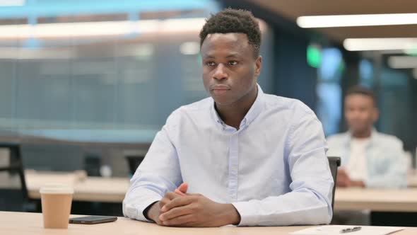 African Businessman Sitting in Office Thinking