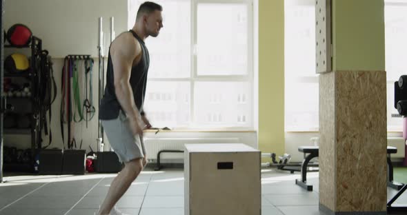 Young Muscular Athlete Works Out in a Modern Gym Making Box Jumps Exercise