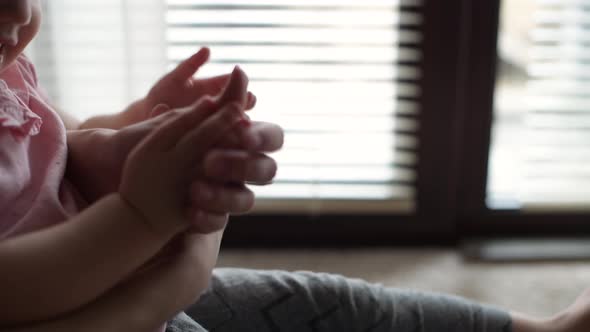 Hands of mom and little daughter who play together near the window