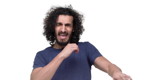 Portrait of Emotional Guy with Curly Hair in Casual Dark Blue Tshirt Gesturing with Hand Over White