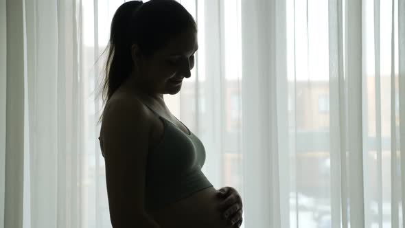 Pregnant Woman Silhouette in Sportswear Strokes Large Belly