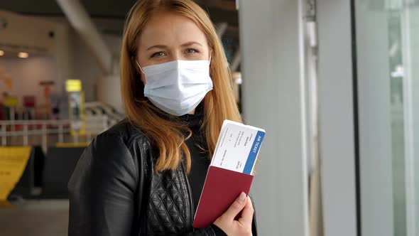 A Woman in a Mask at the Airport She Shows Her Passport with a Plane Ticket