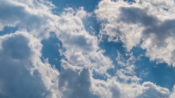 Fast moving clouds in front of a blue sky with sunbeams as a timelapse 4k footage.