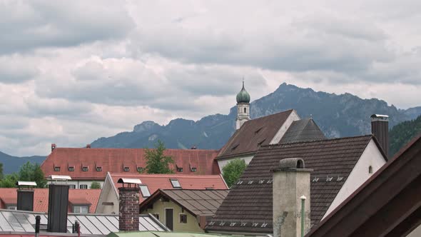 Peaked Roofs of the Houses of Fussen and the Dome on the Background of the Splendor of the Alps.