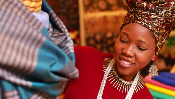 Tanzanian Woman with Snake Print Turban Over Hear Working in Fabrics Shop