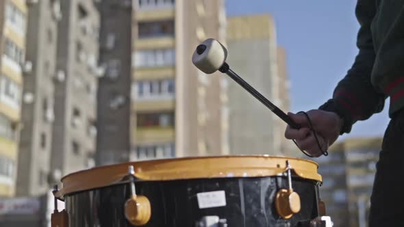 A Man Beats a Drum on the Street