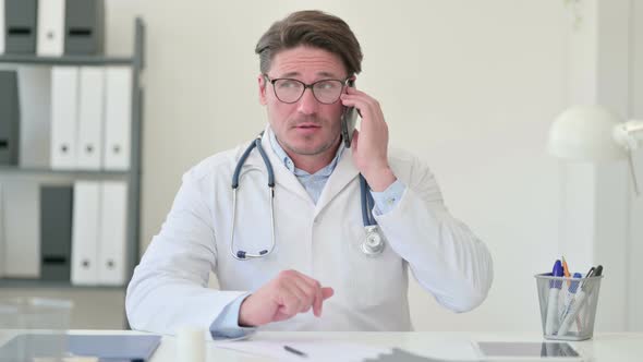 Middle Aged Male Doctor Talking on Smartphone 