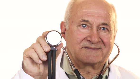 Senior Male Doctor Holding Up a Stethoscope To the Camera