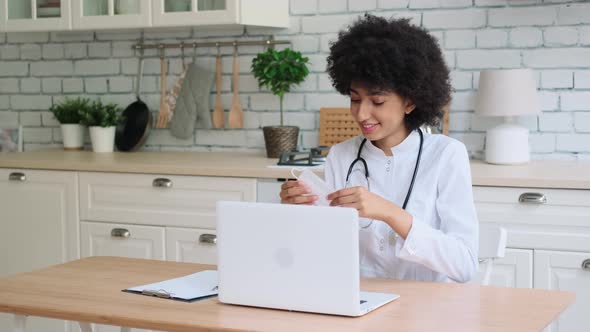 Afro American Woman Doctor Demonstrates Protection of Medical Mask During Online Consultation at
