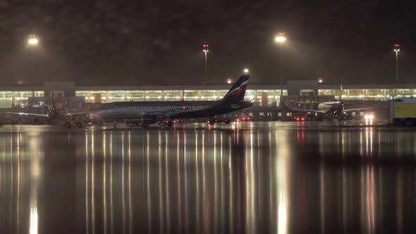 Tow pushbacking Aeroflot plane in Sheremetyevo Airport at rainy night, Moscow