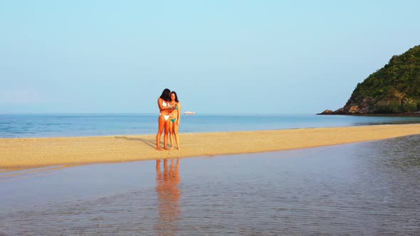 Tourists happy and smiling on idyllic lagoon beach vacation by blue green water and clean sandy back