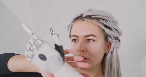 The girl is stroking the robotic arm Bionics Cybernetic Robotic-arm Hand prosthesis