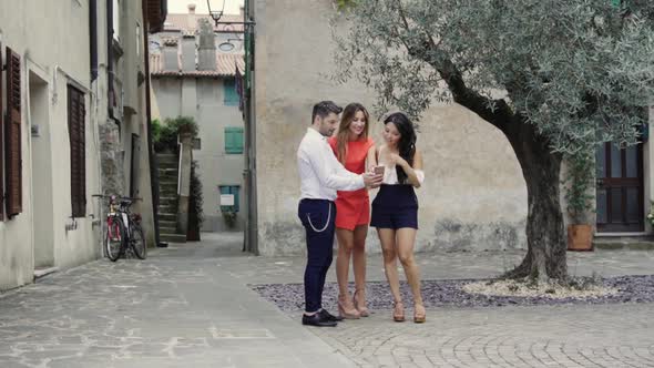 Slow motion shot of three friends using smartphone on square