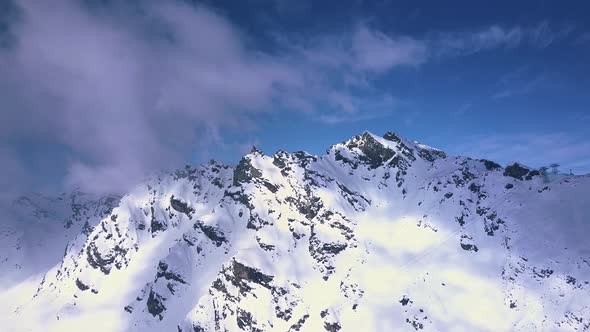 Aerial drone shot of bright sunlight breaking over the white snowy alps and mountains above the vaca