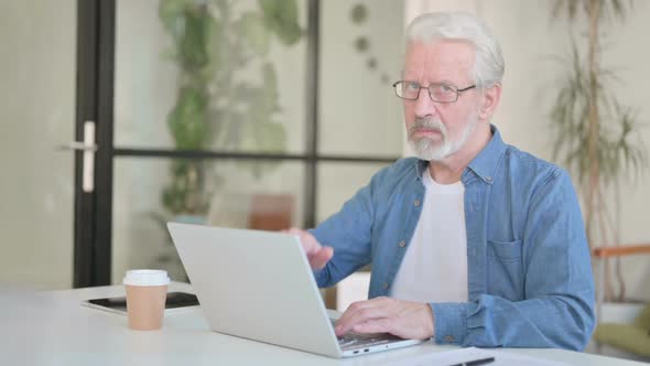 Senior Old Man Showing Thumbs Down While Using Laptop in Office