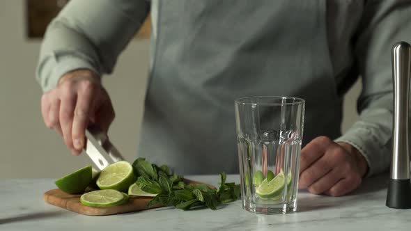 Bartender Puts Lime and Mint Leaves in a Glass to Make a Mojito Cocktail