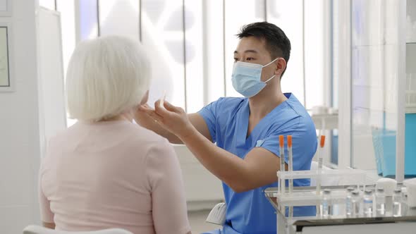 Medical Male w in Protective Mask Taking PCR Test Sample From Throat of Female Mature Patient