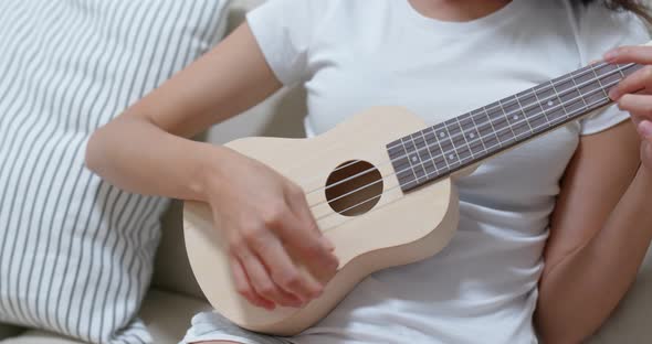 Woman practice ukulele at home