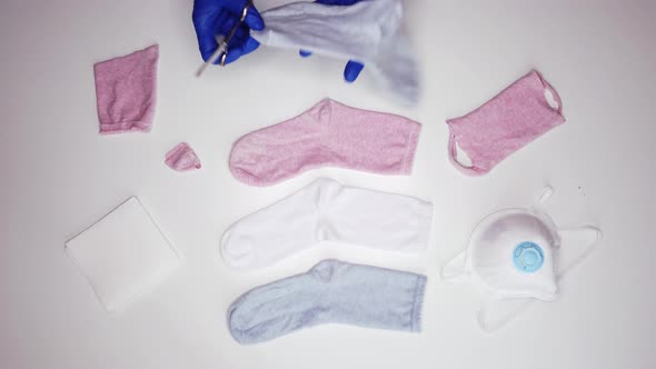 Unrecognizable woman in sterile gloves cutting sock to make mask