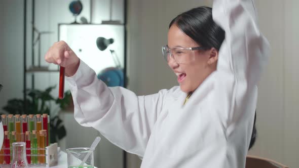 Excited Young Asian Scientist Girl Mixes Chemicals In Test Tube. Child Learn With Interest