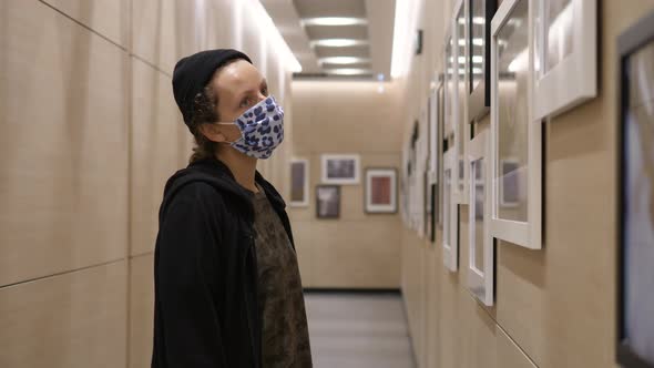 Young Woman Wearing Face Mask Looking at Pictures in Photography Gallery