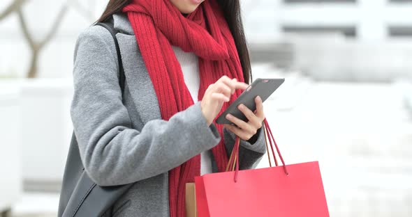 Woman use of smart phone and holding shopping bag