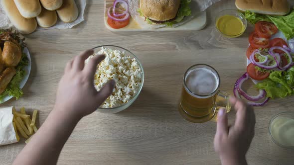 Male Abusing Harmful Food, Eating Full Arms of Popcorn and Drinking Lots of Beer